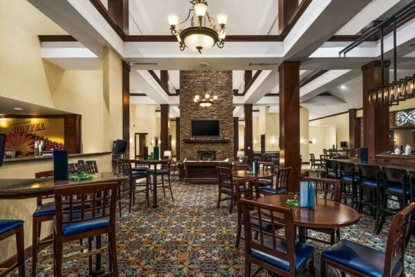 small round tables surrounded by chairs ranging up to the fireplace, chandelier above it