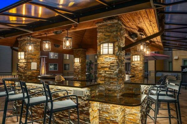 white-cushioned chairs under a glass partial roof on the patio
